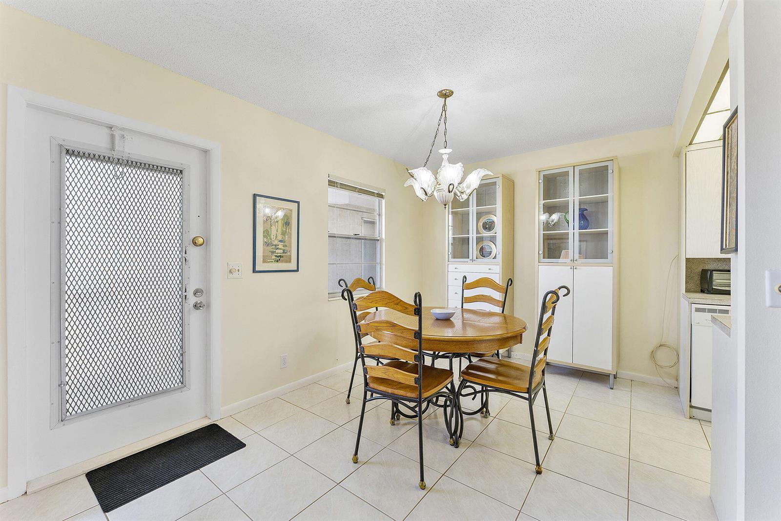 A dining area features a round wooden table, four chairs, and a white china cabinet — 3027 Guildford B, Boca Raton FL 33434, BOCA RATON, FL