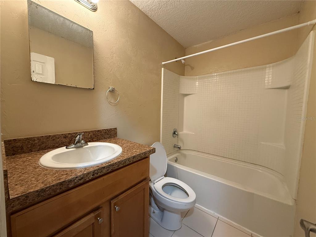 A bathroom features a vanity with a granite countertop, a toilet, and a shower-tub combo — 601 HARDY STREET UNIT 8, BUNNELL, FL