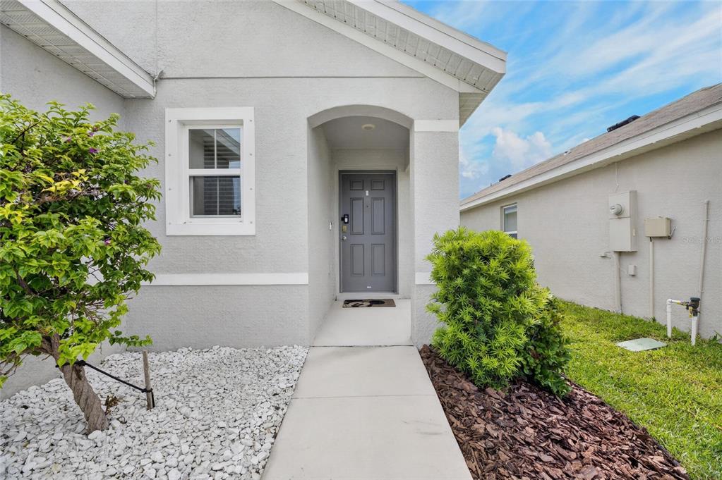 The exterior view shows a gray house entrance with a walkway, landscaping, and a front door — 579 OLIVE CONCH STREET, RUSKIN, FL