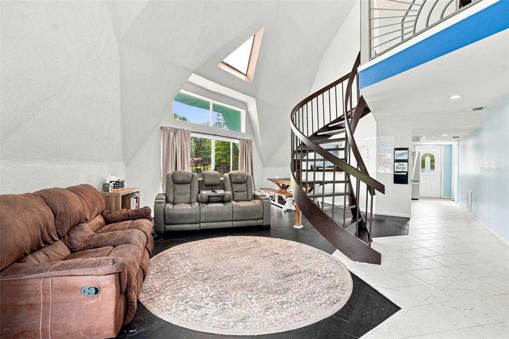 A living room with a spiral staircase, vaulted ceilings, and a brown reclining sofa — 5285 S HILLS POINT, LECANTO, FL