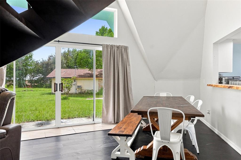A dining area features a wooden table, white chairs, a bench, and sliding glass doors — 5285 S HILLS POINT, LECANTO, FL