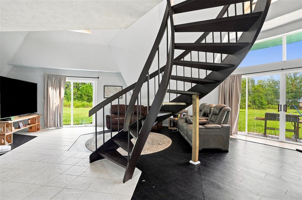 A living room features a dark spiral staircase, tile flooring, and sliding glass doors — 5285 S HILLS POINT, LECANTO, FL