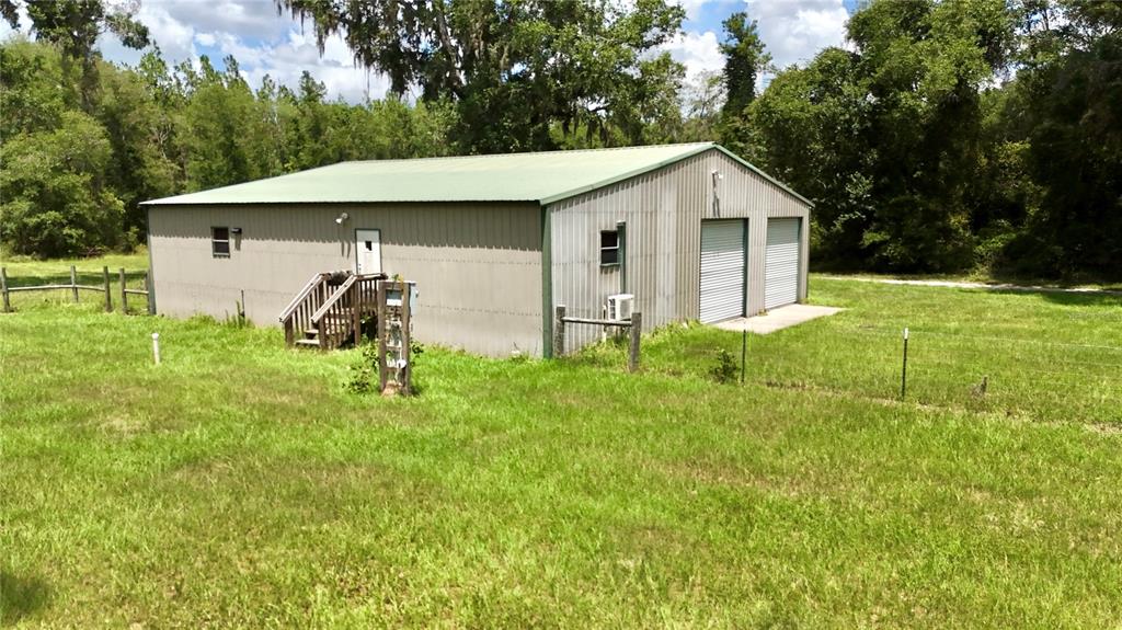 A metal-sided workshop with two garage doors, a side entrance, and a green roof — 2669 NW SUWANNEE VALLEY ROAD, LAKE CITY, FL
