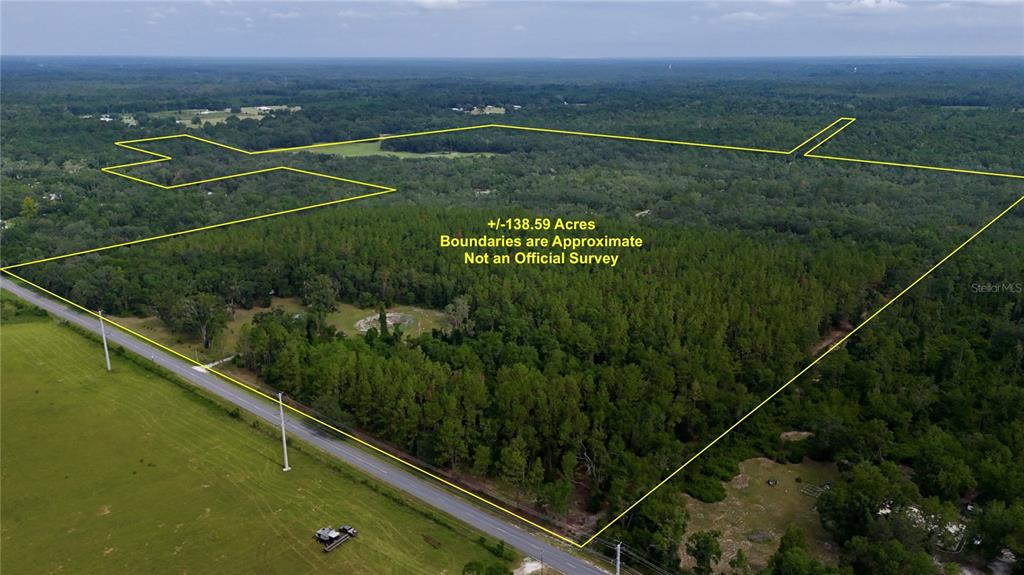 An aerial view shows a large, wooded plot of land outlined in yellow — 2669 NW SUWANNEE VALLEY ROAD, LAKE CITY, FL