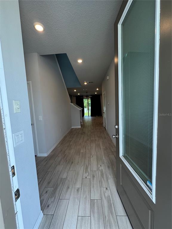 An entryway leads into a long hallway with light wood-look tile flooring and recessed lighting — 4318 HIBISCUS BLOOM DRIVE, ORLANDO, FL