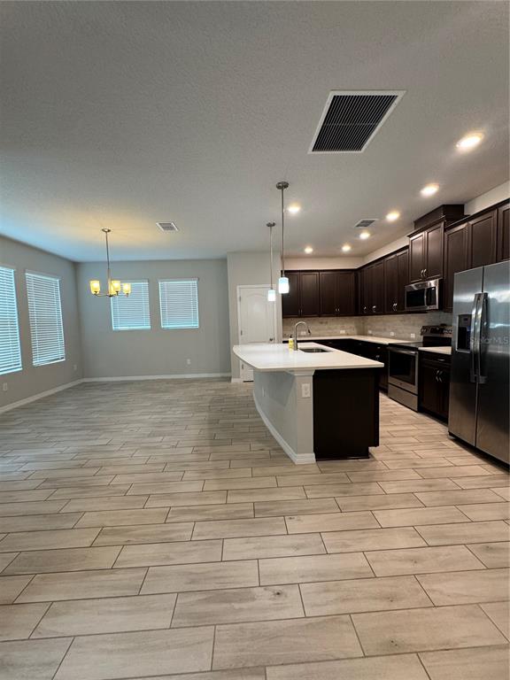 A kitchen with dark cabinets, a white island, and light wood-look tile flooring — 4318 HIBISCUS BLOOM DRIVE, ORLANDO, FL
