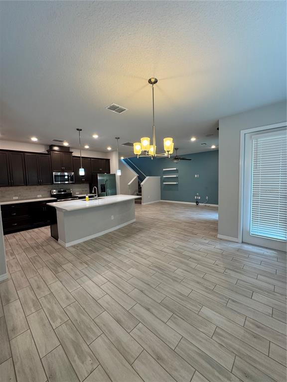 An open-concept kitchen with dark cabinets, a white island, and light wood-look tile flooring — 4318 HIBISCUS BLOOM DRIVE, ORLANDO, FL