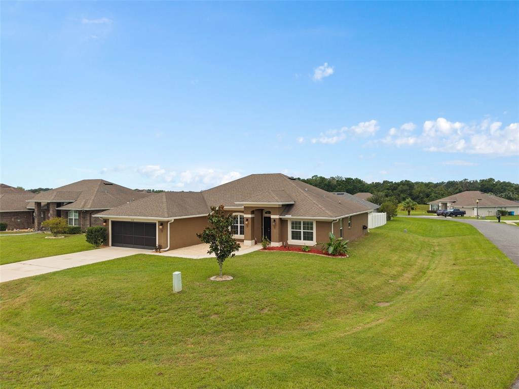 A single-story suburban house with a brown exterior, a two-car garage, and a grassy lawn — 9558 SW 50TH COURT, OCALA, FL