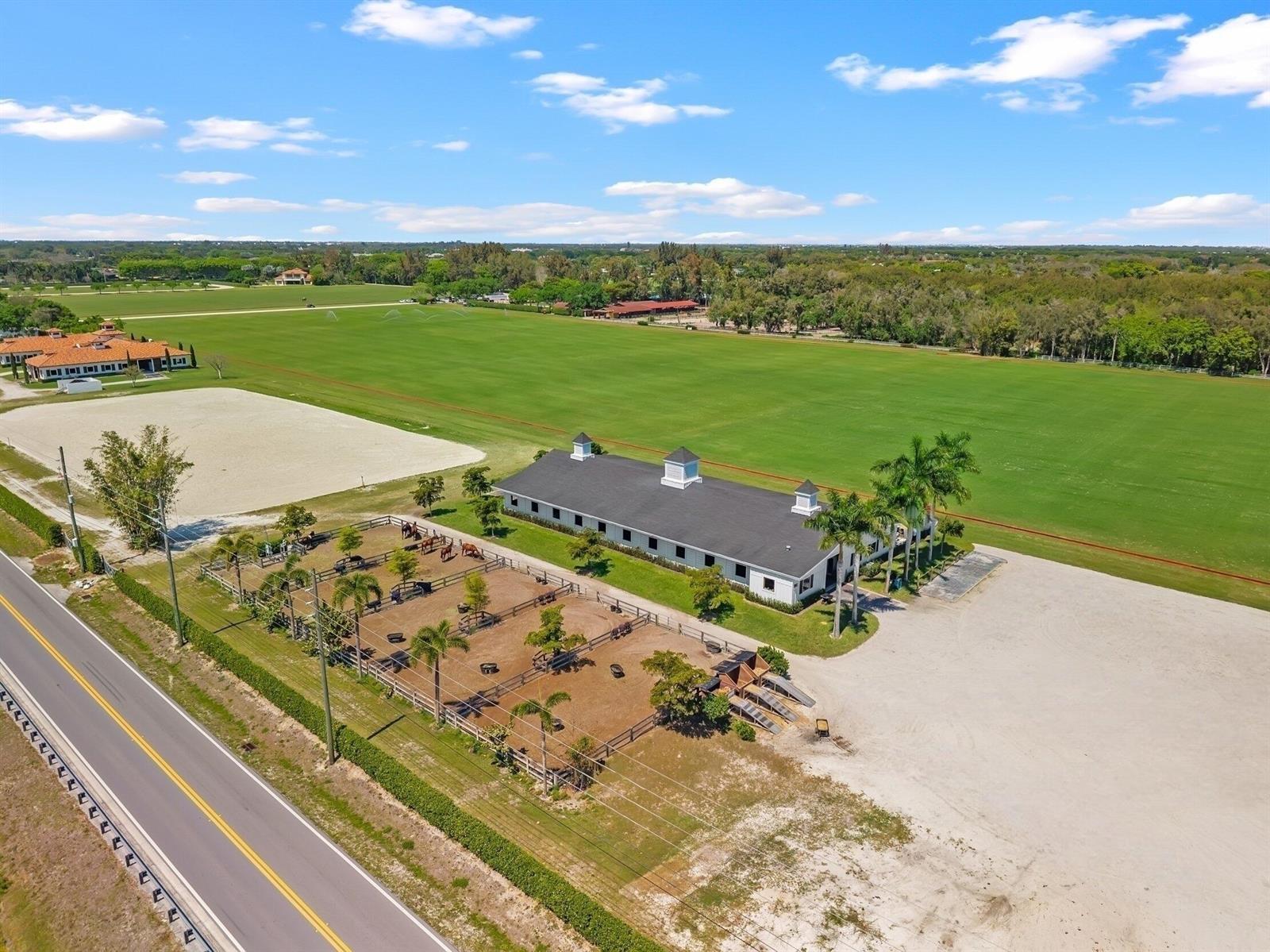 An aerial view shows a horse stable with fenced paddocks next to a large field — 12059 S 50th St S, Wellington FL 33449, WELLINGTON, FL