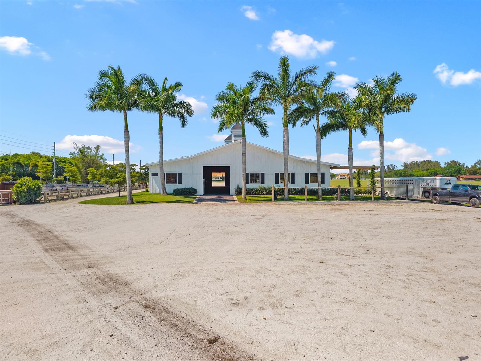 A white barn with palm trees stands in front of a large sandy lot — 12059 S 50th St S, Wellington FL 33449, WELLINGTON, FL