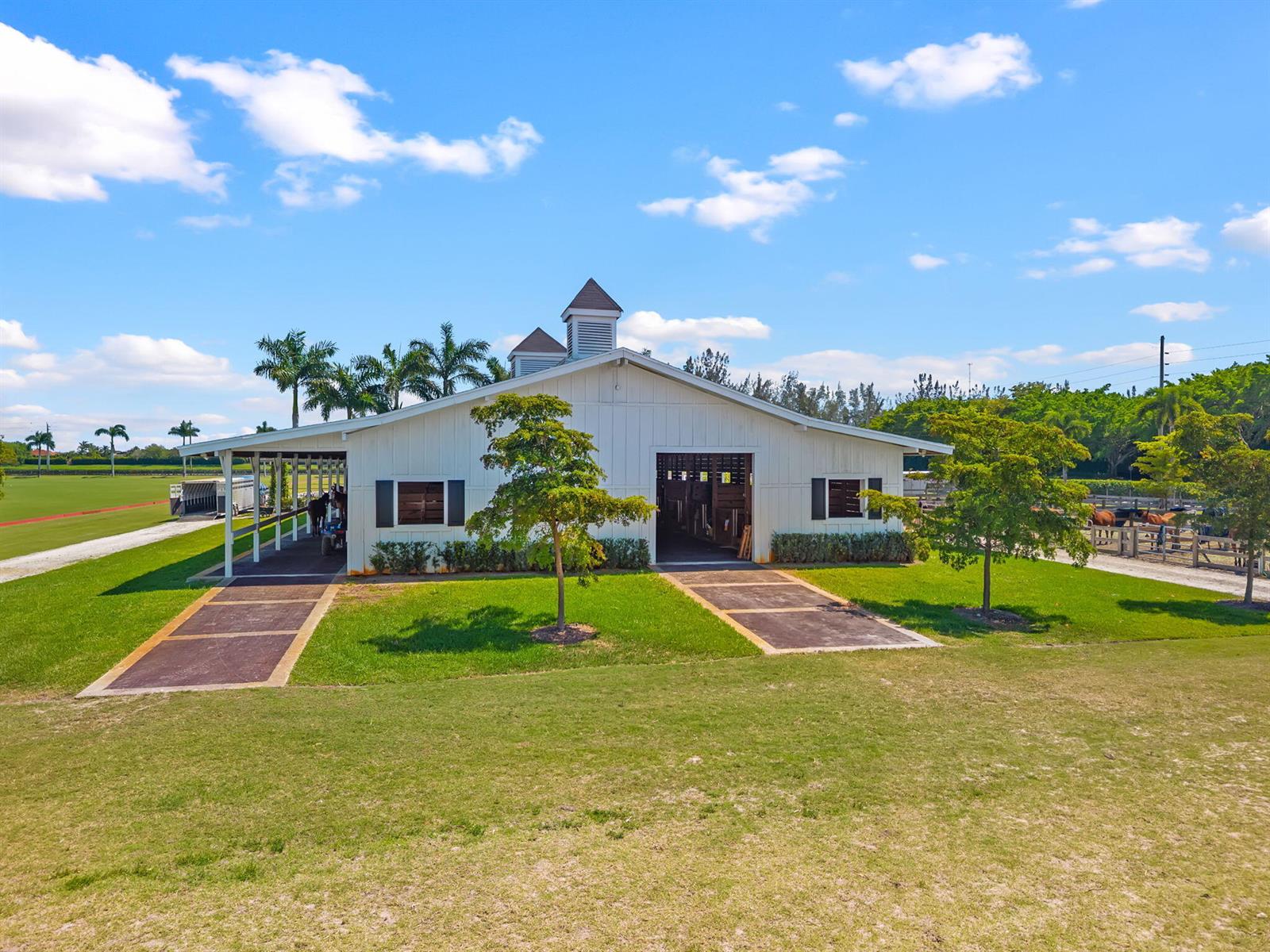 An exterior view of a white barn with a cupola and two paved walkways — 12059 S 50th St S, Wellington FL 33449, WELLINGTON, FL
