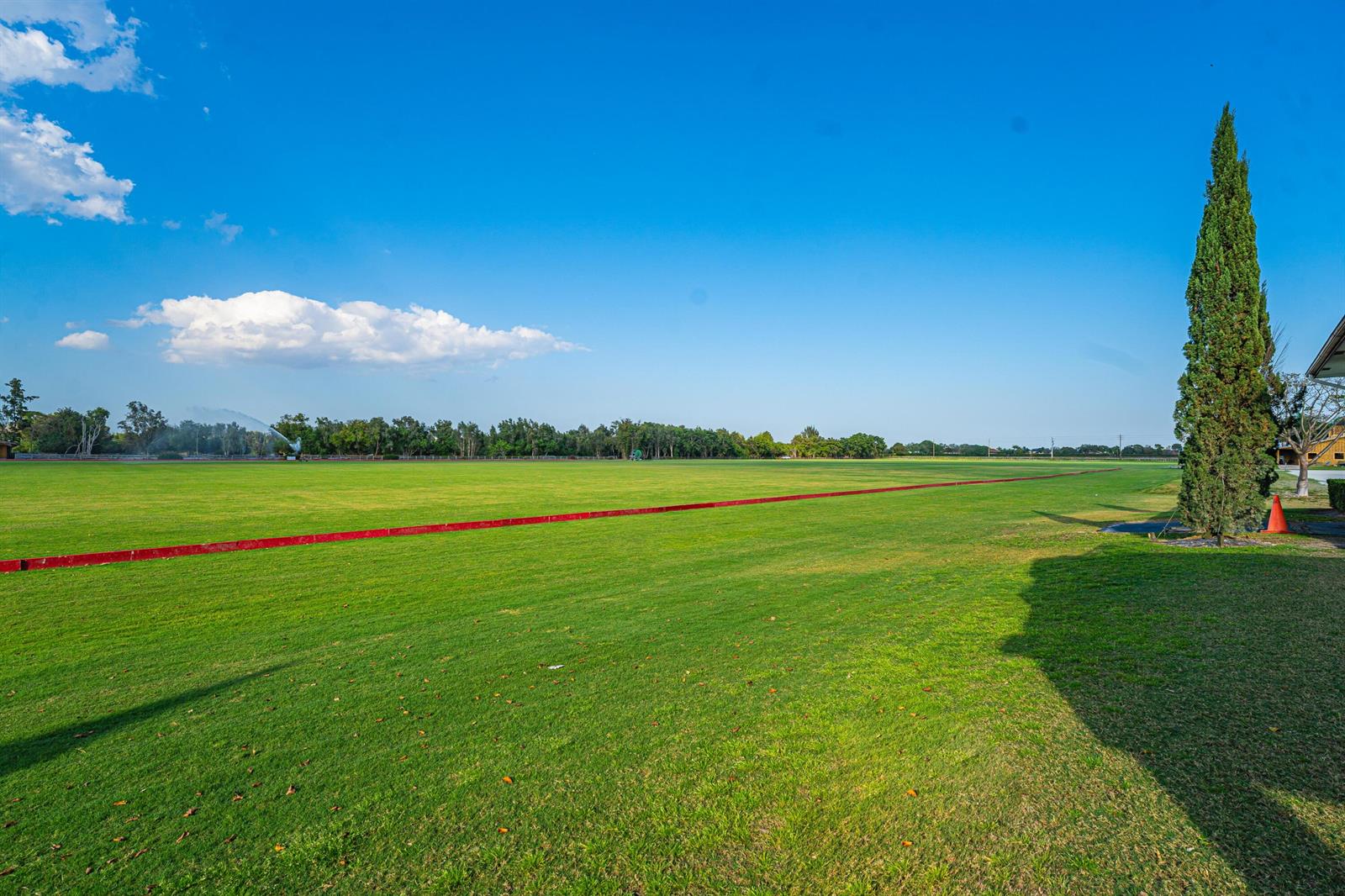 A large, flat green field stretches toward a line of trees under a blue sky — 12059 S 50th St S, Wellington FL 33449, WELLINGTON, FL