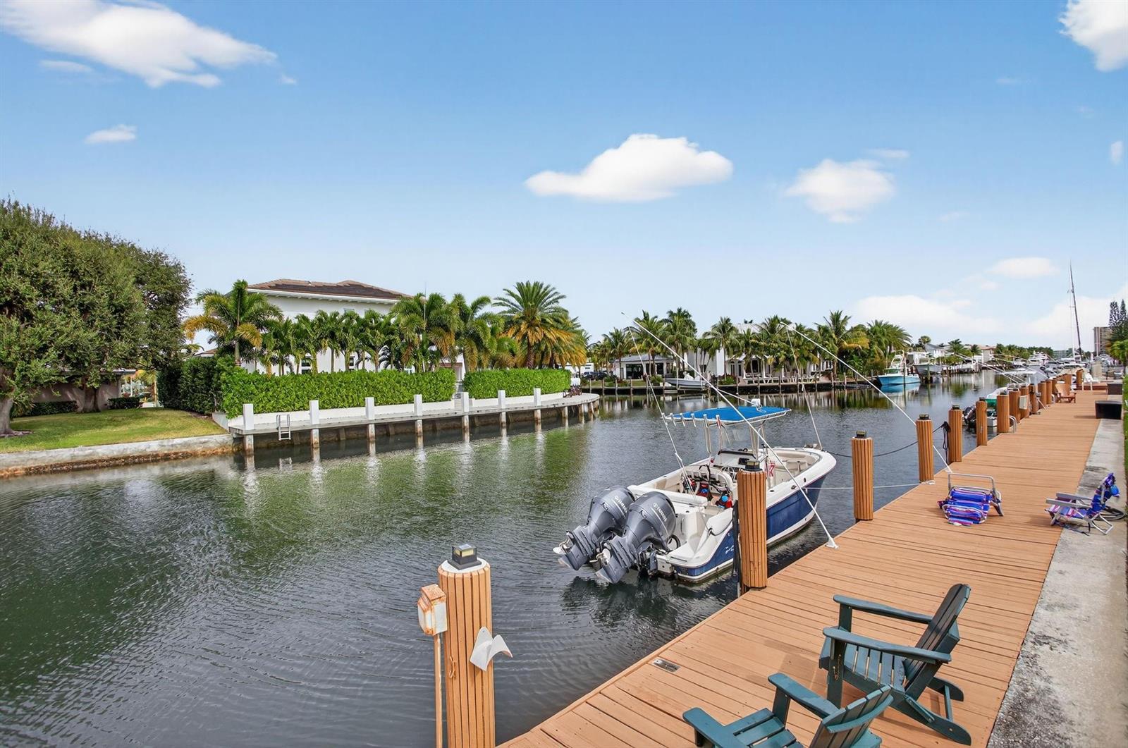 A boat is docked at a wooden pier along a canal lined with palm trees — 2311 NE 36th Street # 1f, Lighthouse Point FL 33064, LIGHTHOUSE POINT, FL