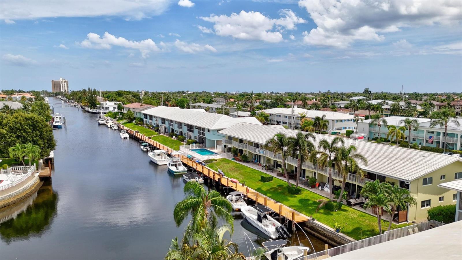 An aerial view shows a canal lined with residential buildings, palm trees, and docked boats — 2311 NE 36th Street # 1f, Lighthouse Point FL 33064, LIGHTHOUSE POINT, FL