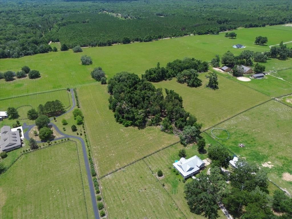 An aerial view shows a rural property with houses, fenced pastures, and patches of trees — TBD SW BLUEBIRD COURT, FORT WHITE, FL