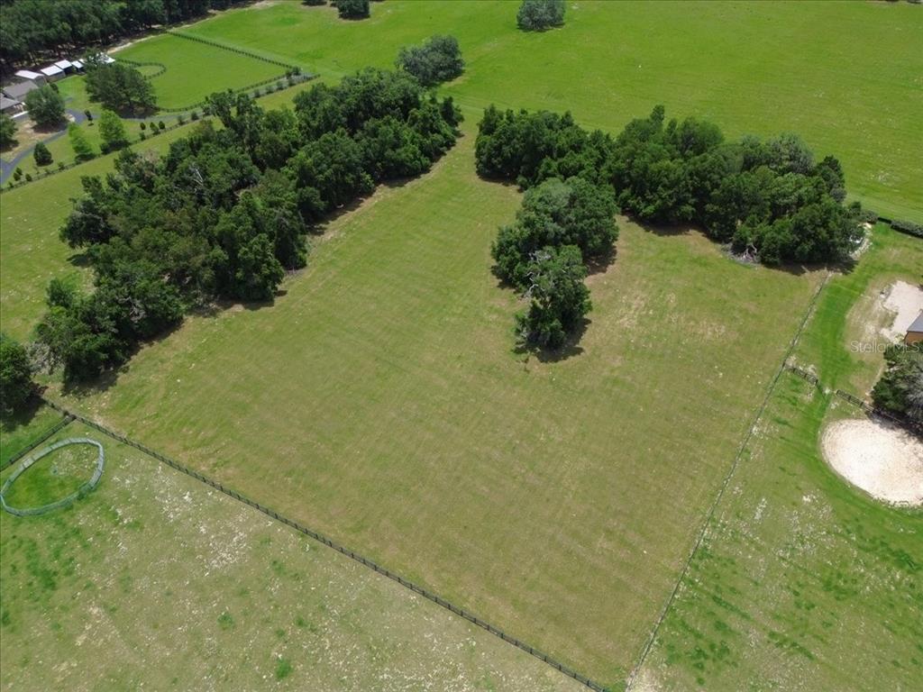 An aerial view shows a large, fenced grassy pasture surrounded by mature trees — TBD SW BLUEBIRD COURT, FORT WHITE, FL