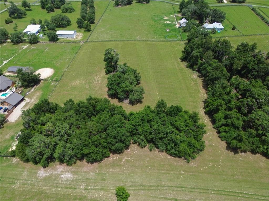 An aerial view shows a large, grassy, fenced lot with clusters of mature trees — TBD SW BLUEBIRD COURT, FORT WHITE, FL