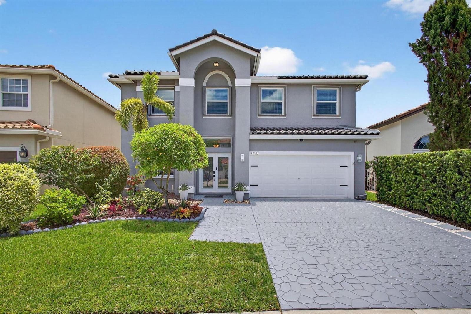 A two-story gray house with a white garage door and a patterned concrete driveway — 3738 Old Lighthouse Circle, Wellington FL 33414, WELLINGTON, FL