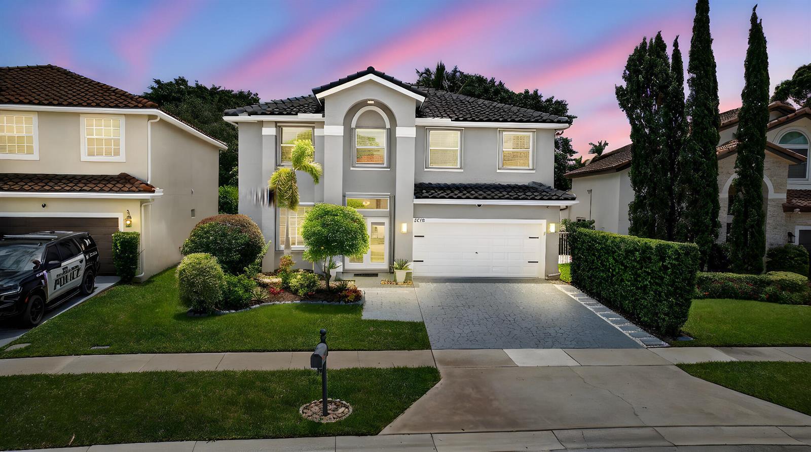 A two-story gray house with a white garage and a police vehicle parked outside — 3738 Old Lighthouse Circle, Wellington FL 33414, WELLINGTON, FL