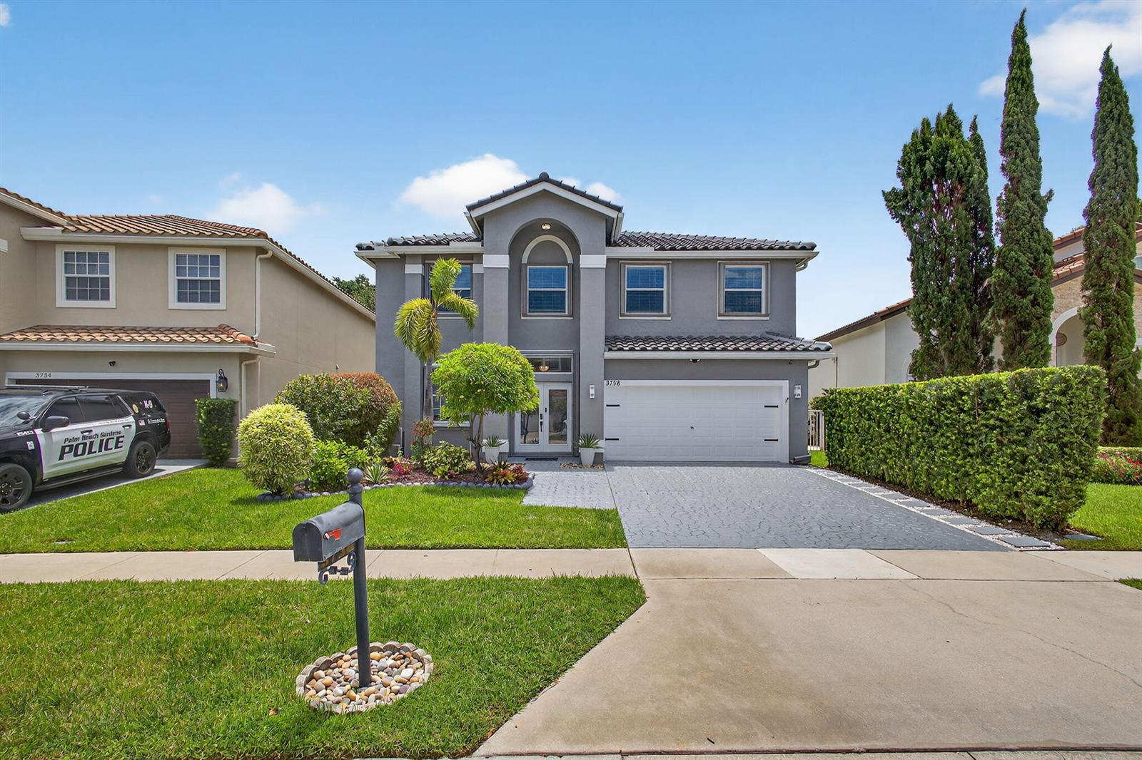 A two-story gray house with a two-car garage and a police vehicle parked outside — 3738 Old Lighthouse Circle, Wellington FL 33414, WELLINGTON, FL
