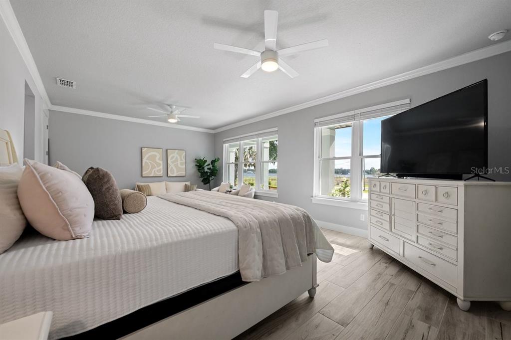 A spacious open-concept living room features light wood-look tile flooring, gray furniture, and recessed lighting — 590 LAKE WINNEMISSETT DRIVE, DELAND, FL