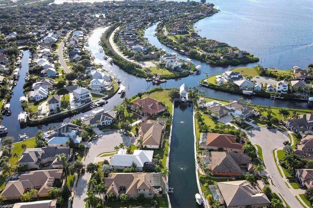 An aerial view shows waterfront homes situated along canals leading into a large bay — 4747 PINNACLE DRIVE, BRADENTON, FL