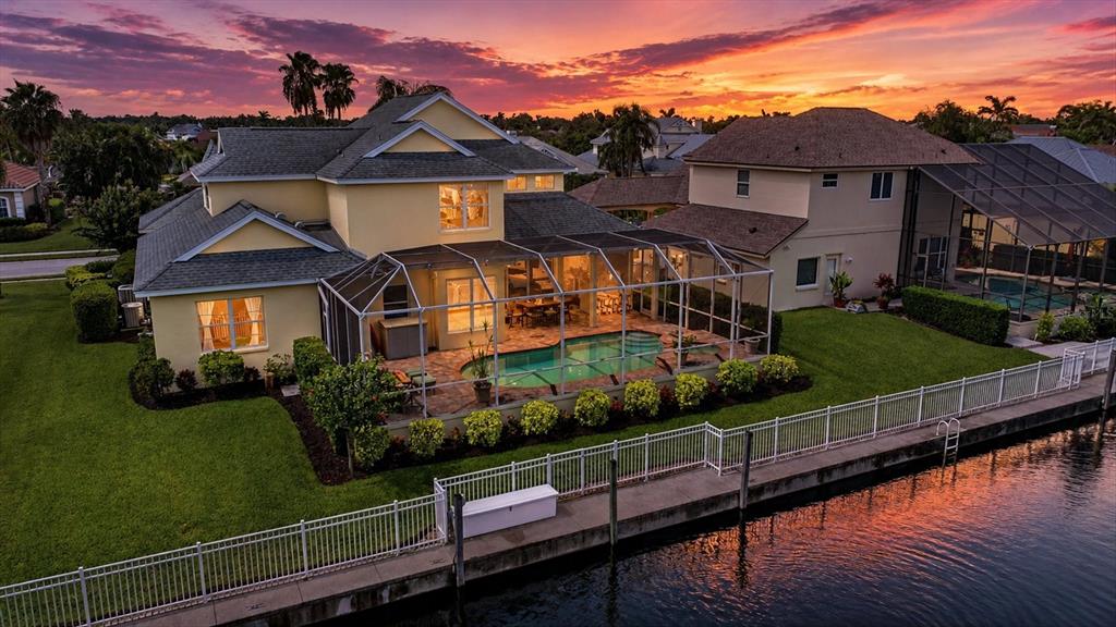 An aerial view of a two-story house with a screened-in pool overlooking a canal — 4747 PINNACLE DRIVE, BRADENTON, FL
