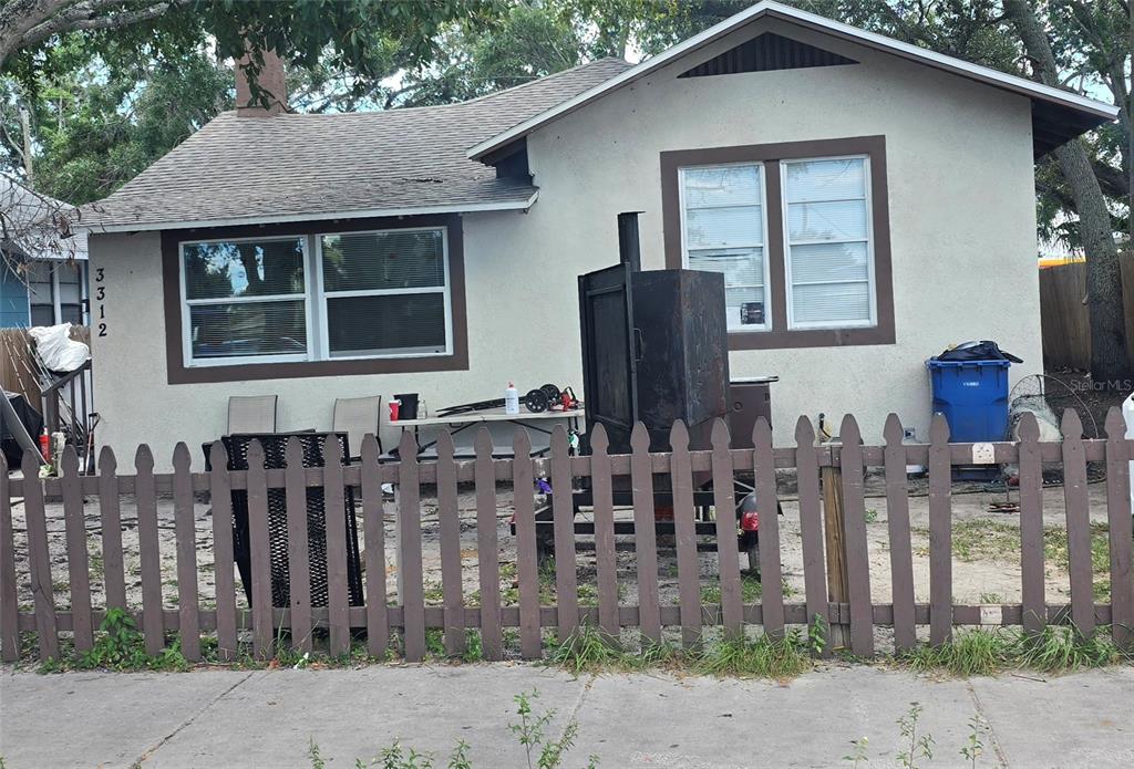 A single-story house with a brown picket fence and a large smoker on the lawn — 3312 QUEENSBORO AVENUE S, ST PETERSBURG, FL
