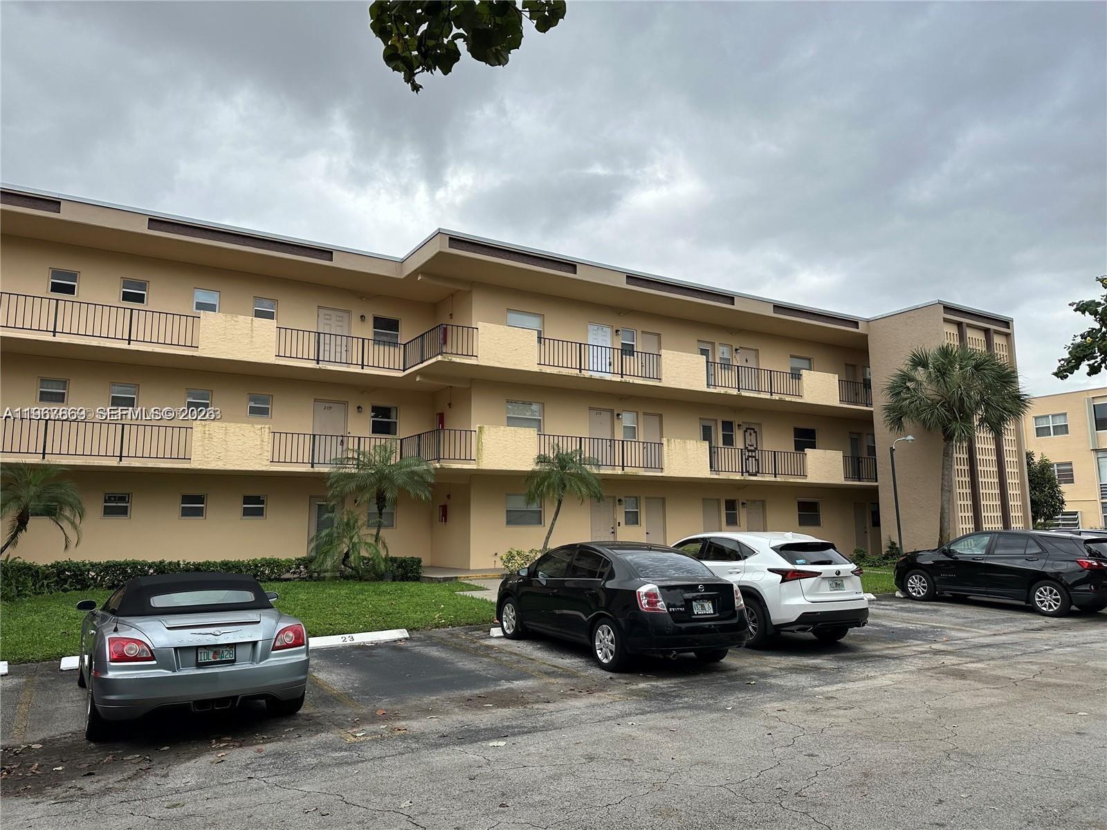 A three-story apartment building with exterior walkways and a parking lot in front — 200 Ashbury Rd # 209, Hollywood FL 33024, HOLLYWOOD, FL