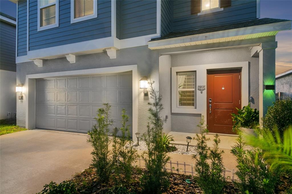 The exterior of a two-story home features a gray garage, a red front door, and landscaping — 1418 AUSTIN STREET, WINTER HAVEN, FL