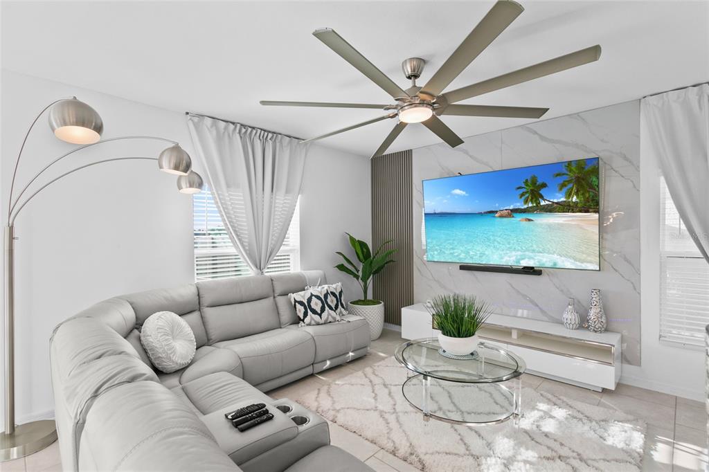 A living room features a grey sectional sofa, a wall-mounted television, and a ceiling fan — 1418 AUSTIN STREET, WINTER HAVEN, FL