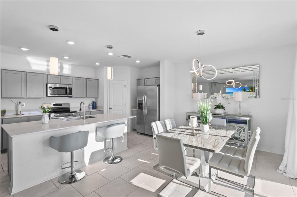 A modern kitchen and dining area featuring gray cabinets, a white island, and tile flooring — 1418 AUSTIN STREET, WINTER HAVEN, FL