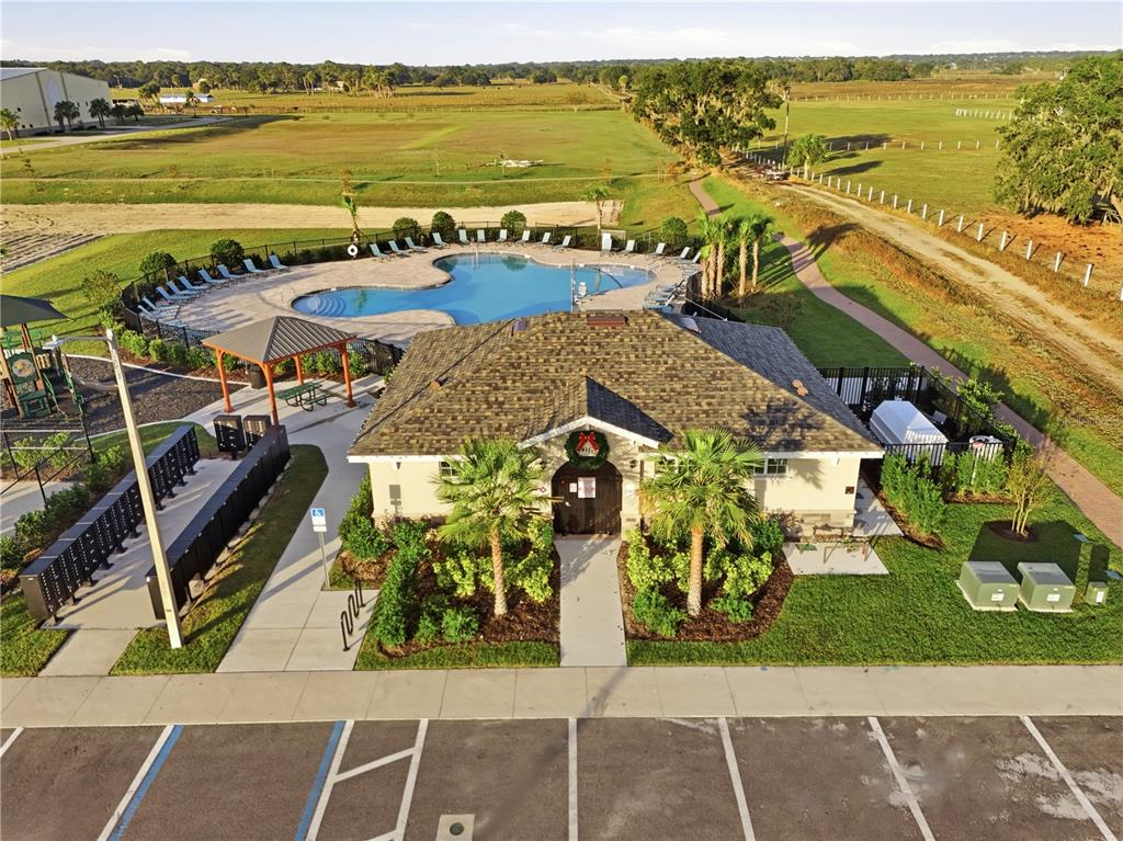 An aerial view shows a community clubhouse with a pool, playground, and parking lot — 4207 HILLOCK BOULEVARD, HAINES CITY, FL