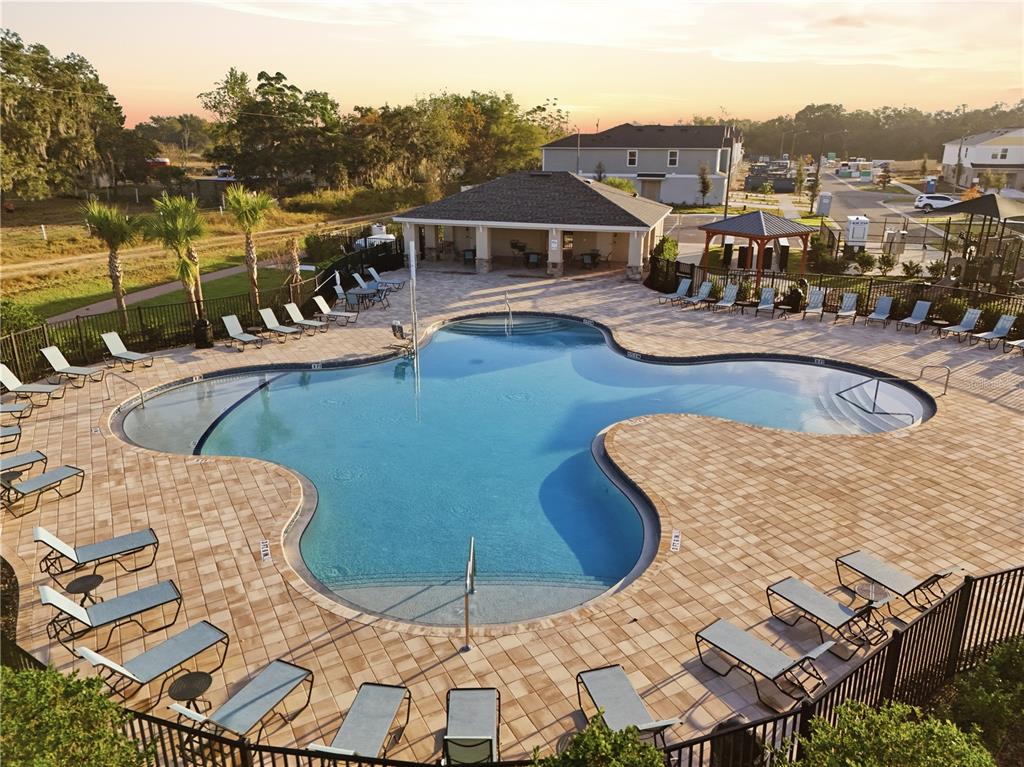 An aerial view of a community swimming pool surrounded by lounge chairs and a clubhouse — 4207 HILLOCK BOULEVARD, HAINES CITY, FL