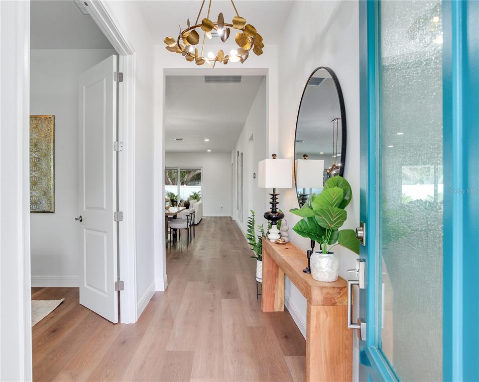 A bright entryway features light wood flooring, a gold leaf chandelier, and a console table — 2814 54TH STREET S, GULFPORT, FL
