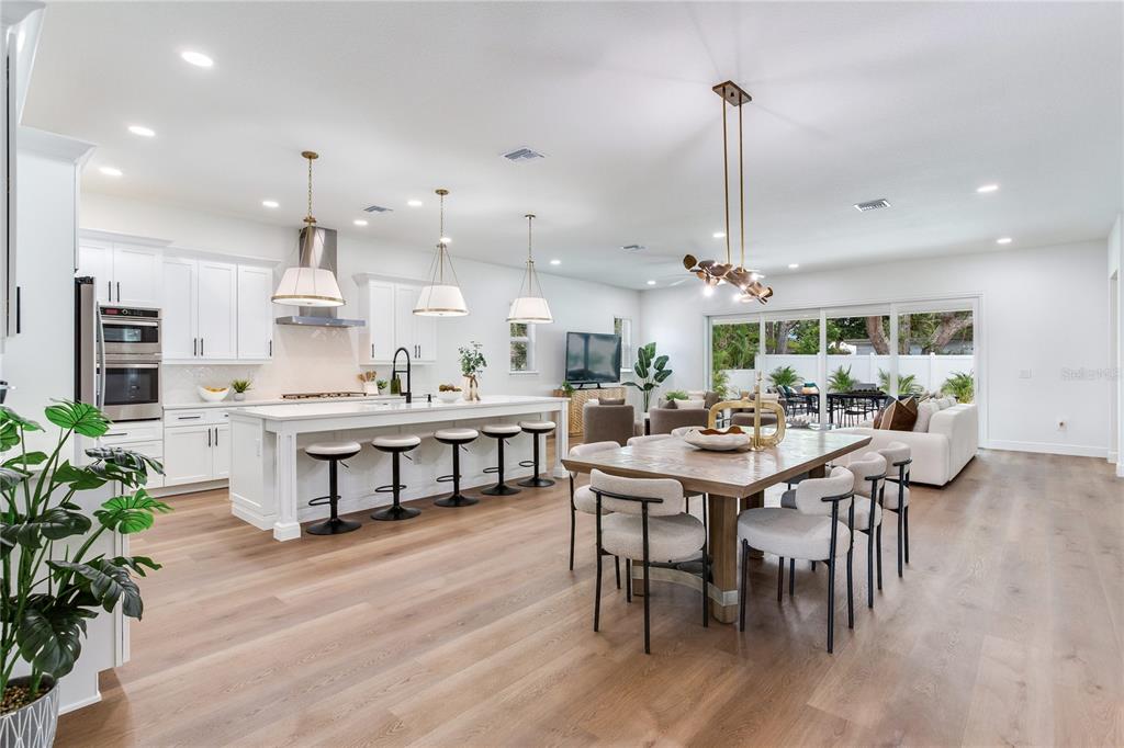 A bright, open-concept kitchen and dining area features white cabinetry, a large island, and wood floors — 2814 54TH STREET S, GULFPORT, FL