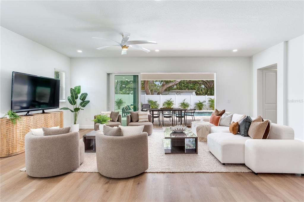 A modern living room features light wood floors, a white sectional, and sliding doors to a pool — 2814 54TH STREET S, GULFPORT, FL