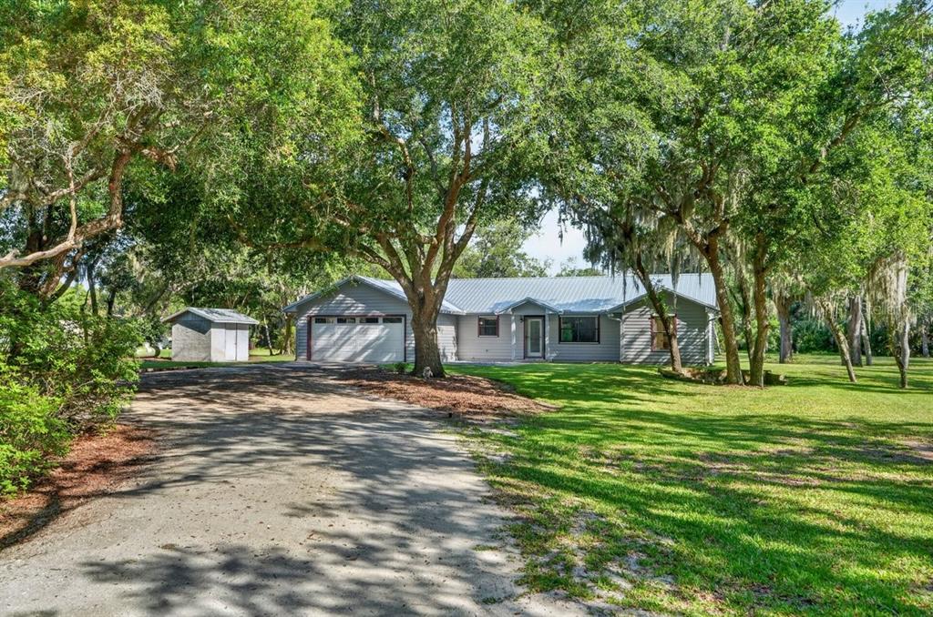 A single-story gray house with a metal roof sits behind a large tree-lined driveway — 171 WILLIAM STREET, EDGEWATER, FL