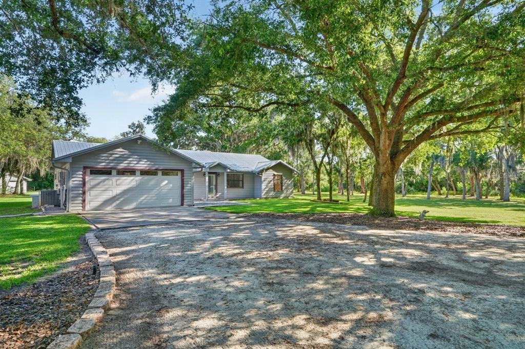 A gray house with a metal roof and attached garage sits on a grassy lot — 171 WILLIAM STREET, EDGEWATER, FL