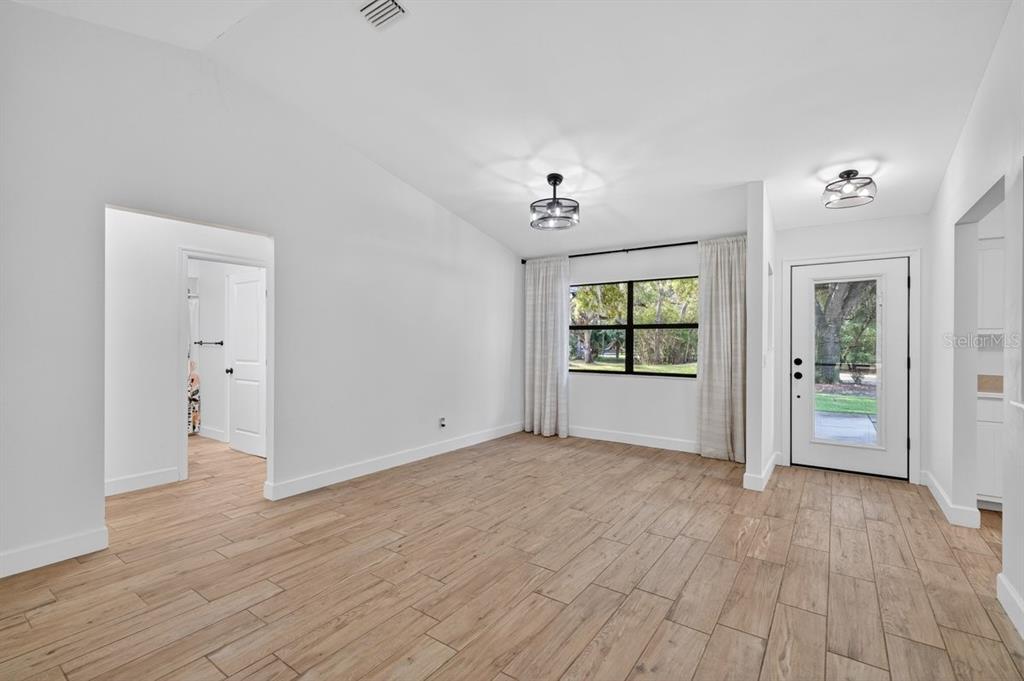 A bright room with wood-look tile flooring, a window with curtains, and a glass-paneled door — 171 WILLIAM STREET, EDGEWATER, FL