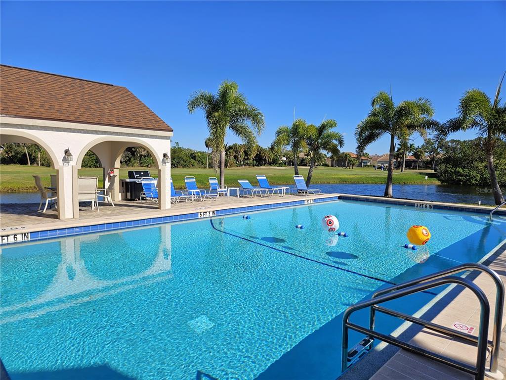 A swimming pool with a covered patio area sits beside a pond and golf course — 812 CAPRI ISLES BOULEVARD UNIT 225, VENICE, FL