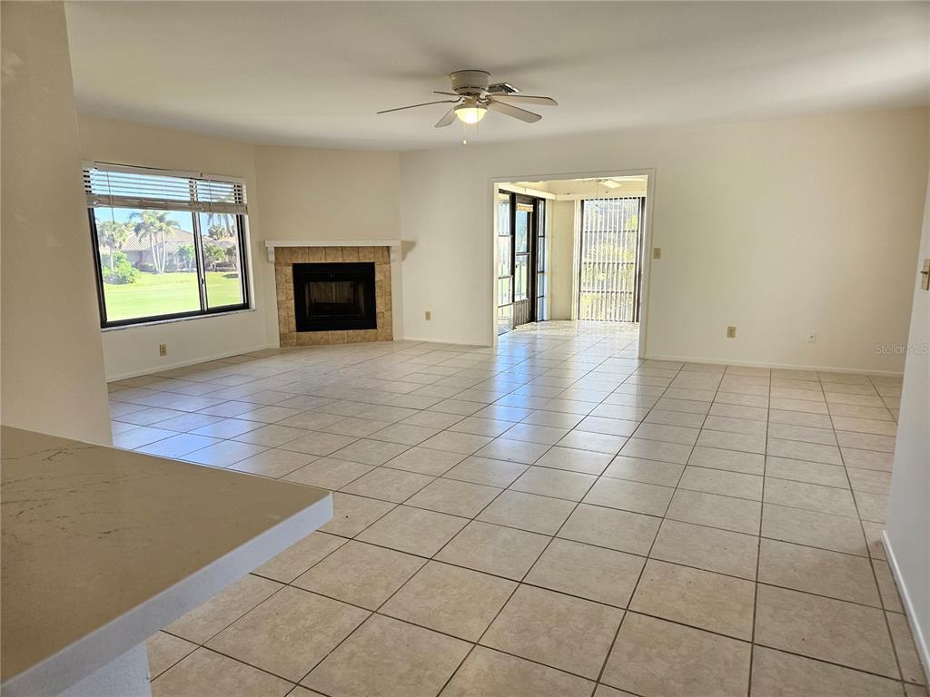A living room with tile flooring, a fireplace, a ceiling fan, and a screened patio — 812 CAPRI ISLES BOULEVARD UNIT 225, VENICE, FL
