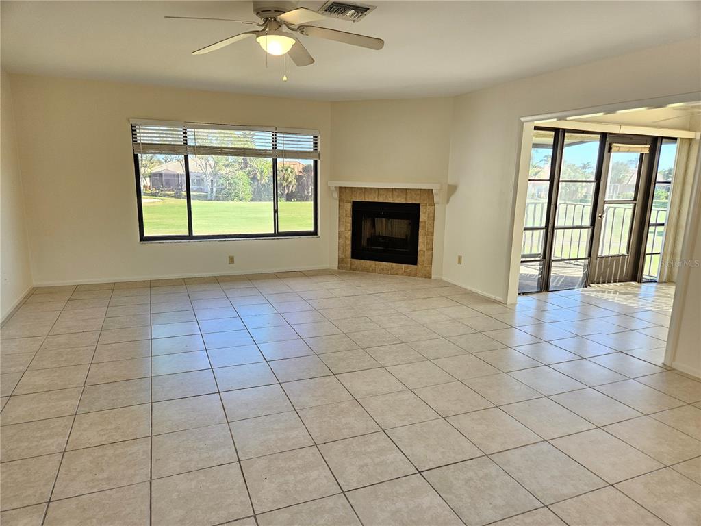 A living room with tile flooring, a corner fireplace, and a view of a golf course — 812 CAPRI ISLES BOULEVARD UNIT 225, VENICE, FL