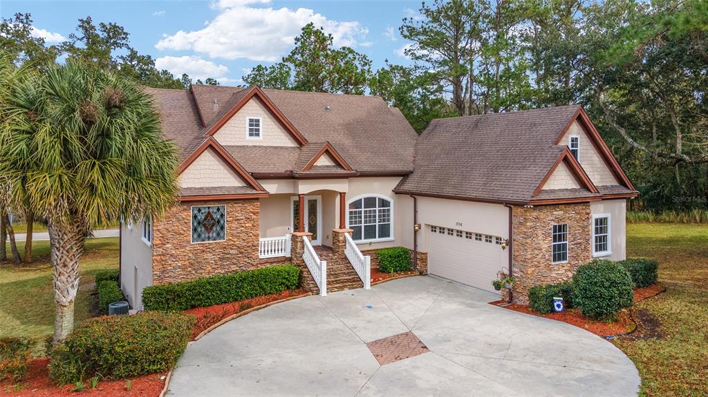 A two-story house with stone siding, a shingled roof, and a circular concrete driveway — 1706 SW 27TH STREET, OCALA, FL