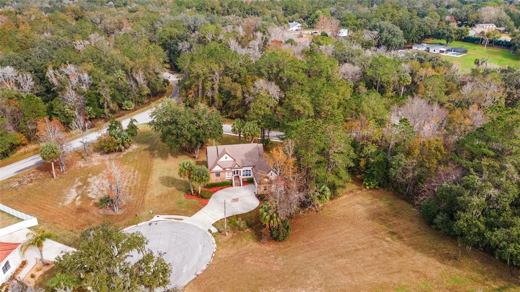 An aerial view shows a house with a circular driveway surrounded by trees and grass — 1706 SW 27TH STREET, OCALA, FL