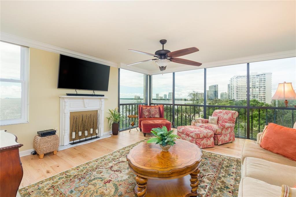 A living room with a fireplace, ceiling fan, and floor-to-ceiling windows overlooking the water — 2407 S ARDSON PLACE UNIT 601, TAMPA, FL