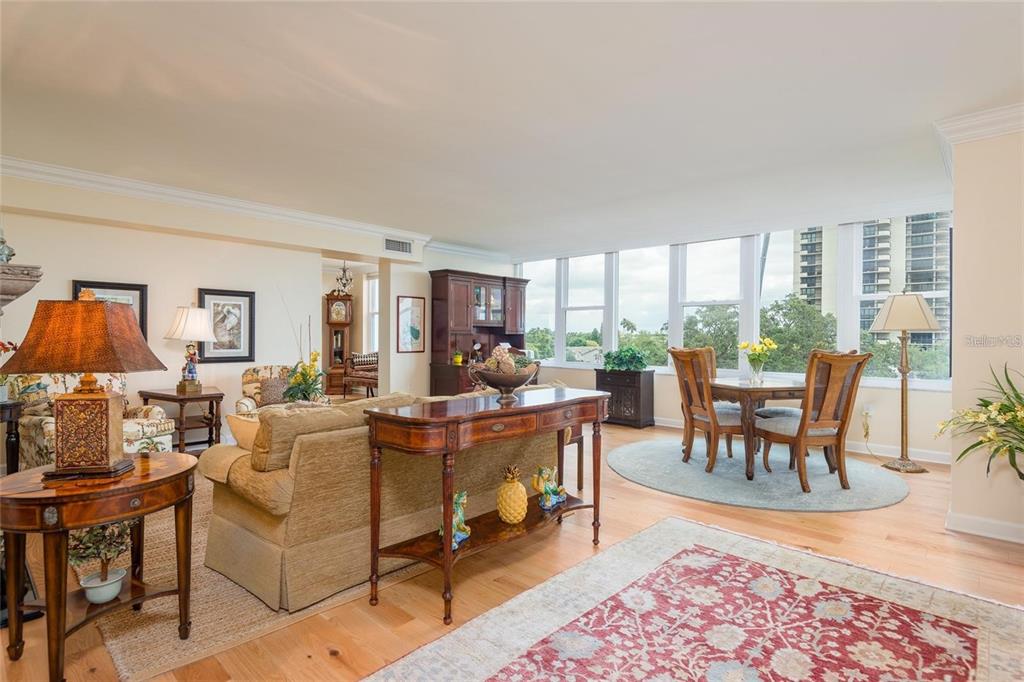 A living and dining room with hardwood floors, a sofa, and large windows overlooking trees — 2407 S ARDSON PLACE UNIT 601, TAMPA, FL