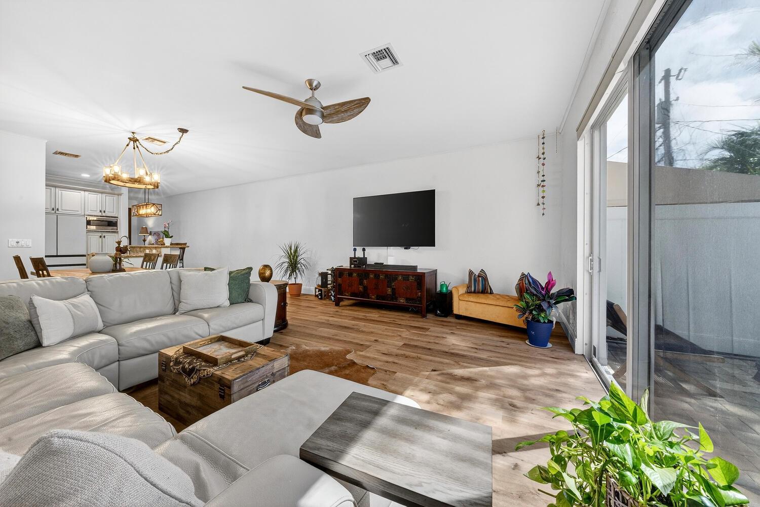 A living room with a large sectional sofa, wood flooring, and a wall-mounted television — 1942 NE 32nd Street, Lighthouse Point FL 33064, LIGHTHOUSE POINT, FL