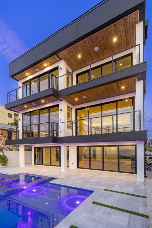 A three-story modern home with balconies, large glass sliding doors, and a swimming pool — 70 GULF BOULEVARD, INDIAN ROCKS BEACH, FL
