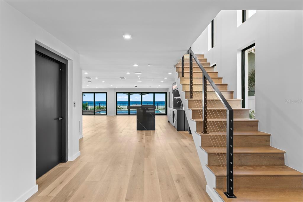 A modern entryway features a blue mosaic tile water wall, stone steps, and glass doors — 70 GULF BOULEVARD, INDIAN ROCKS BEACH, FL